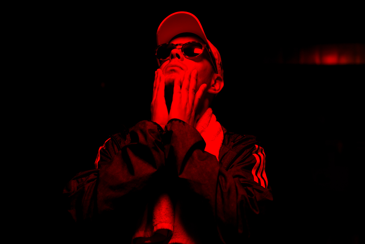 Trettmann in roter Beleuchtung vor schwarzem Hintergrund